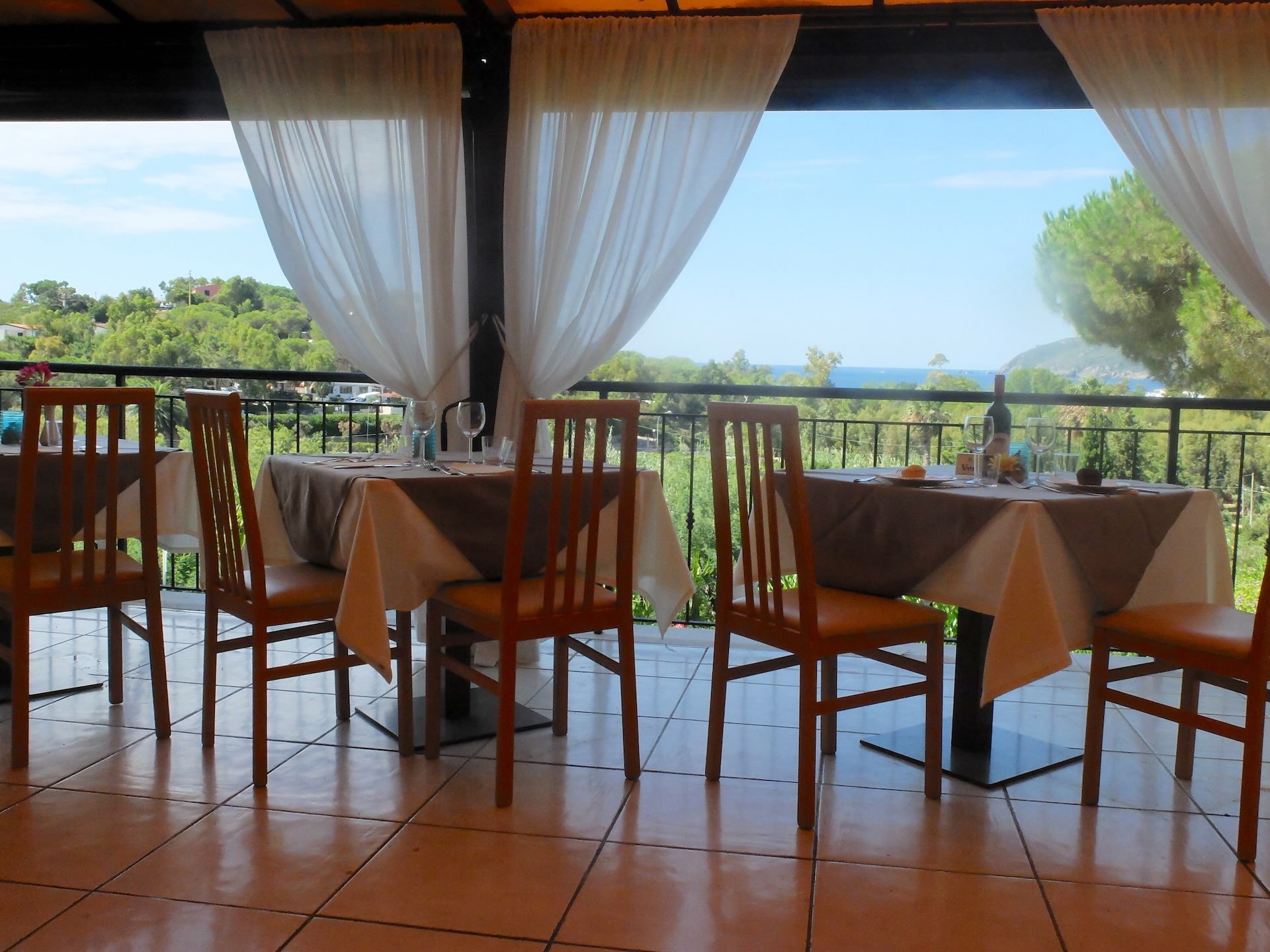 Sala ristorante dell’Hotel Villa Giulia con ampie vetrate e terrazza panoramica affacciata sul verde e sul mare dell’Isola d’Elba.