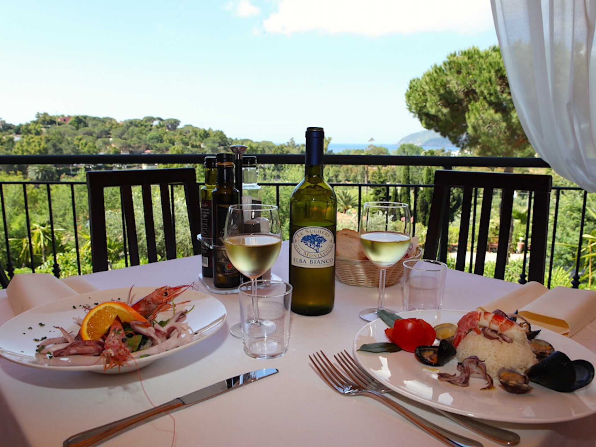 Tavolo apparecchiato sulla terrazza panoramica del ristorante dell’Hotel Villa Giulia con vista sul mare e sulle colline dell’Isola d’Elba.